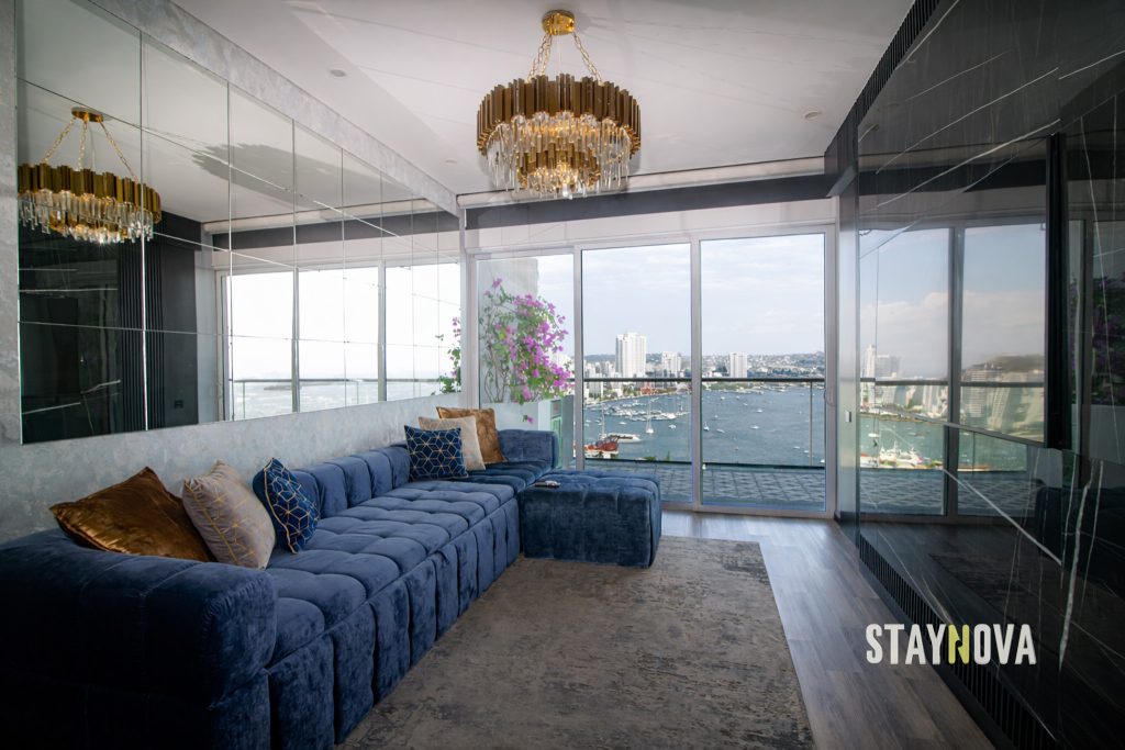 Sala de una propiedad de alquiler turístico de Staynova, con sofá azul, lámpara de cristal y vista a la bahía